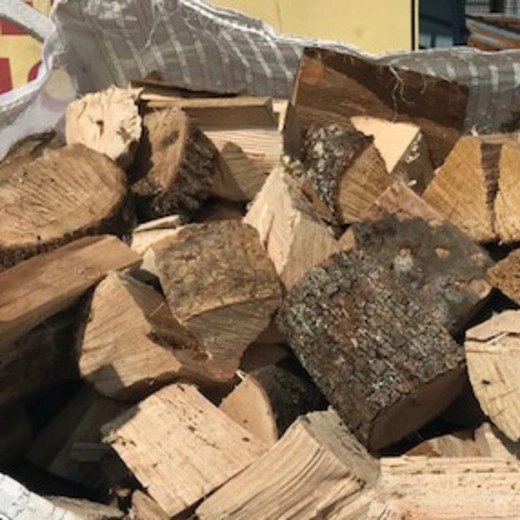 Bûches de bois prêtes à être utilisées devant une cheminée allumée, offrant une chaleur réconfortante